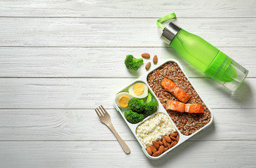 Container with natural healthy lunch, bottle of water and space for text on table, top view. High protein food