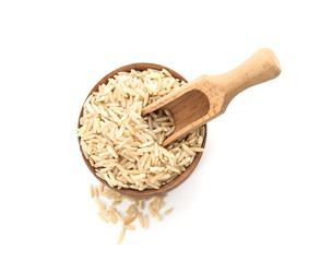 Bowl and scoop with raw unpolished rice on white background, top view