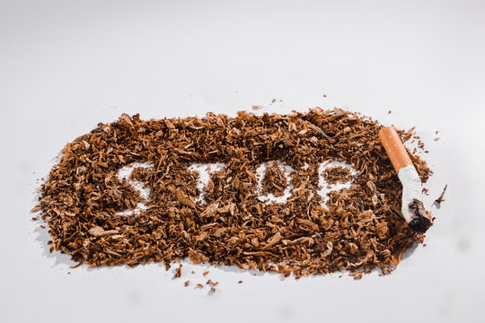 Creative background word stop written in tobacco on white background. The concept of smoking kills, nicatine poisons, cancer from smoking, stop smoking. Copy space.