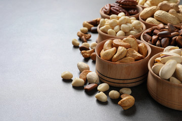 Fototapeta na wymiar Bowls with organic nuts on grey background, space for text. Snack mix
