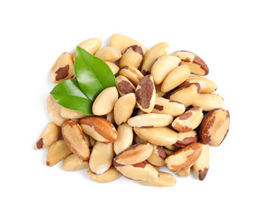 Brazil nuts with green leaves on white background, top view