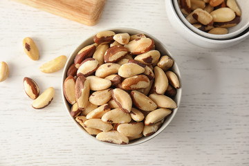 Bowls with tasty Brazil nuts on white wooden table, top view