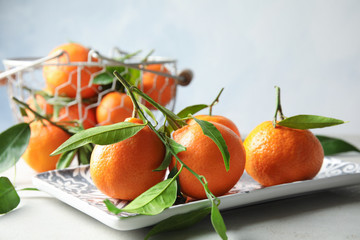 Plate with tasty ripe tangerines on table