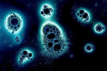 Abstract pattern of bubbles or drops on dark background, various hues of blue
