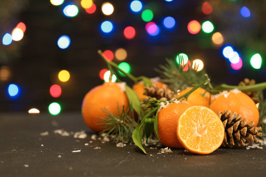 Ripe tangerines, artificial snow and blurred Christmas lights on background. Space for text