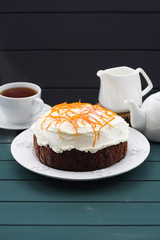 Homemade chocolate fruit cake with cream cheese and orange peel on dark blue background