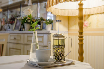 French press, a cup of tea and a white rose