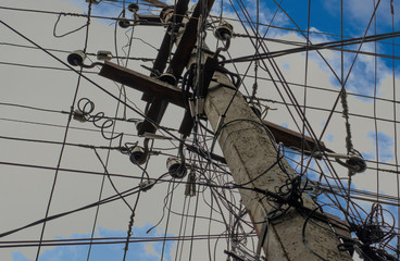 Concrete electric pole against the blue sky with clouds close-up