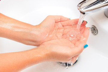 Female hands under running water in the sink - 241325280