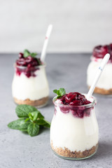 Healthy dessert of natural yogurt, cookies and cherries served with mint. Portion desert in glass. Copy space.