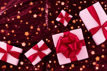 A group of light pastel pink boxes tied with a red satin ribbon with a bow of pop-pop.