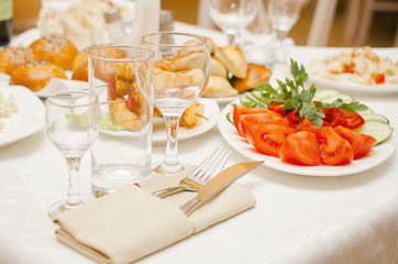 The evening table in the restaurant before dinner is covered with fresh tomatoes and herbs. Serving glasses of wine and juice.
