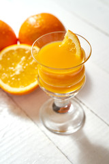 Glass of freshly made orange juice with fruits on an white table.