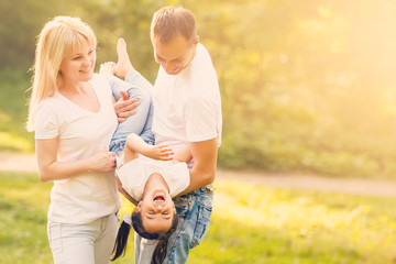 Happy family: mother father and child daughter on nature on sunset