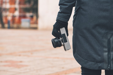Hipster female photographer holding vintage SLR camera on street