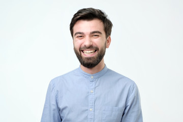 Hispanic man wearing blue shirt laughing or grinning having cheerful look.