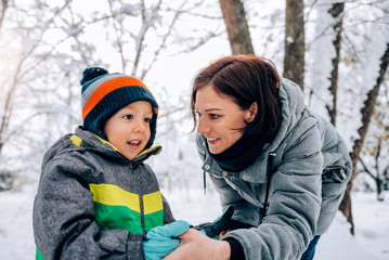 Fototapeta na wymiar Mother helping son putting on snow gloves