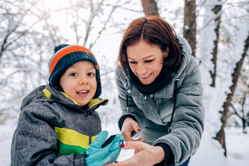 Mother helping son putting on snow gloves