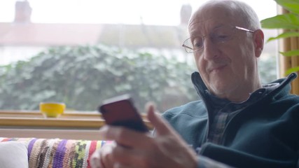 Senior man using a phone at home