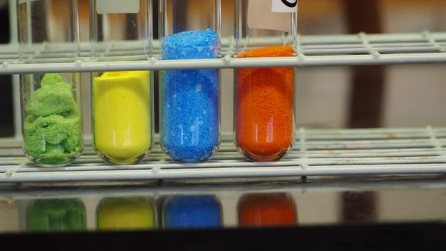 Different colored inorganic chemical salts used in a chemistry lab.