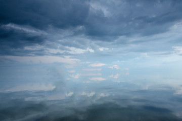 Obraz premium Textural clouds covered the sky over the ocean. The surface of the ocean is calm and reflects the clouds.