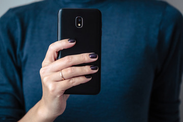 Black mobie smart phone in woman/s hands with perfect dark violet manicure