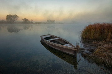 Boat on the river bank on a foggy morning