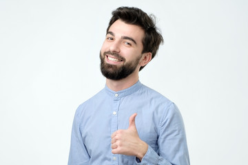 Smiling man showing thumbs up and looking at camera. Handsome guy advertising something.