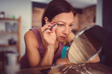 Woman correcting eyebrows shape with Tweezers