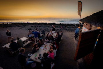 Blurred defocused people in a bar on the beach at the sunset Travel and party concept with group of people enjoying beverage Men and women toasting at the sea party Group of person drinking cocktails