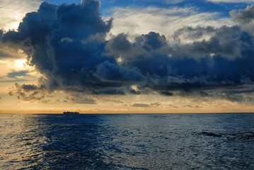 Obraz premium Seascape of a container ship heading out to sea under a morning cloudy sky.