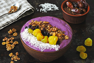Colorful healthy acai bowl. Breakfast bowl with purple smoothies, granola and dried fruit.