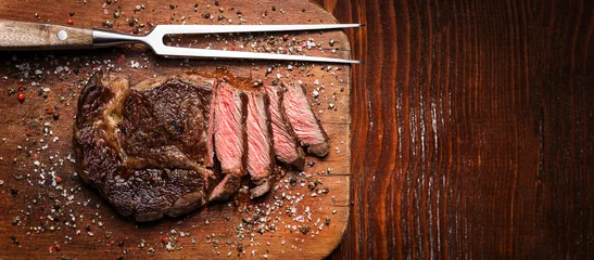 Foto auf Alu-Dibond Leckeres und frisches, sehr saftiges Ribbey-Steak aus marmoriertem Rindfleisch, auf einem Holztisch. © Mikhaylovskiy 