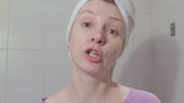 Woman without make up with towel o her head singing a song and shake her head close up