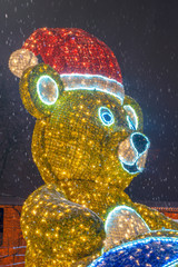 big new year's bear of colorful bulbs on the street on a snowy day