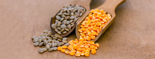 assortment-unpolished red lentils, polished yellow lentils in wooden spoons. banner