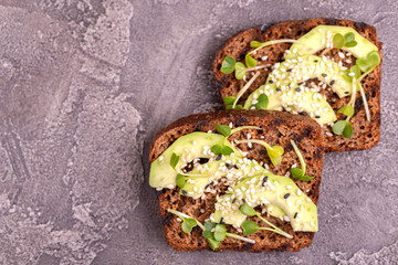 Tasty rye toasts with avocado, radish sprouts and sesame