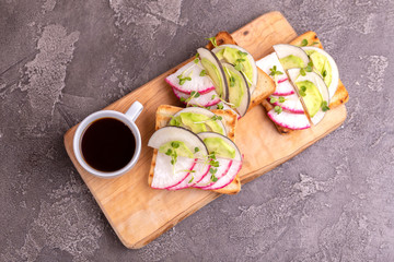 Tasty toasts with radish, avocado and sprouts, cup of coffee
