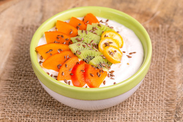 Acai bowl with vanilla smoothie, persimmon, kiwi, kumquat and flaxseeds