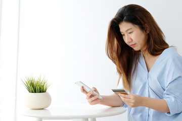 Young asian woman holding credit card and using smart phone for shopping online, business and technology concept, online payment, digital money