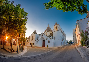 Townscape of Trullo village and religious church architecture Saint Antonio edifice in Alberobello, Italy