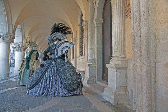 Venice Carnival masks and  costumes under the arcade of the Doges Palace St. Mark's Square