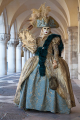 Venice Carnival mask and  comtume under the arcade of the Doges Palace St. Mark's Square