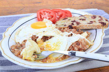Eating Eggs Over Easy on Corned Beef with Tomato and Raisin Toast