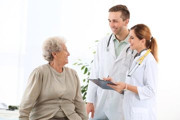 Doctor and medical assistant working with elderly patient in hospital