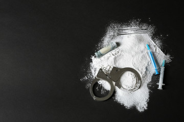 Composition with heap of cocaine, syringes and space for text on black background, top view