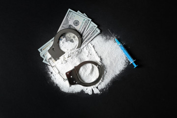 Composition with heap of cocaine and syringe on black background, top view