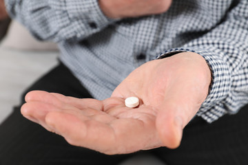 Obraz premium Senior man holding pill in hand, closeup