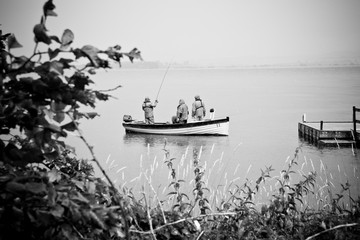Fishermen on a boat on a lake a rainy day, black and white photo.