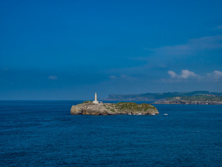 Santander / Hiszpania - 14 lipca 2018: Widok na Latarnię morską na wyspie Mouro z P&oacute;łwyspu La Magdalena - Santander w słoneczny lipcowy dzień